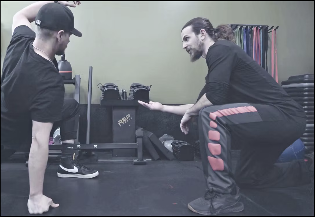 Lifters Guild coach demonstrating dumbbell technique with a member