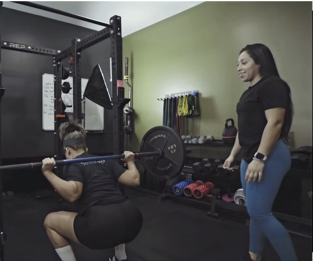 Lifters Guild coach guiding a member through a barbell back squat